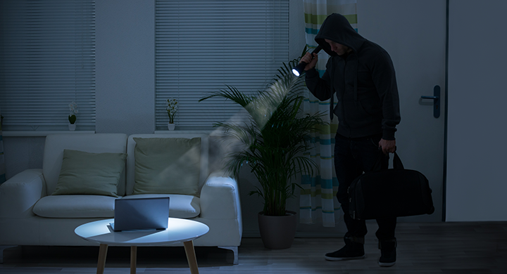  Burglar in a Dark House Shining a Flashlight on a Laptop