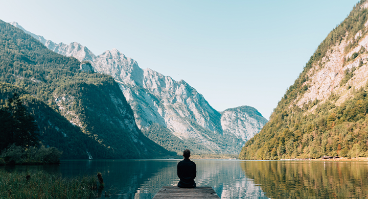 Person Sitting on a Dock Looking at Mountains - Toggle Insurance