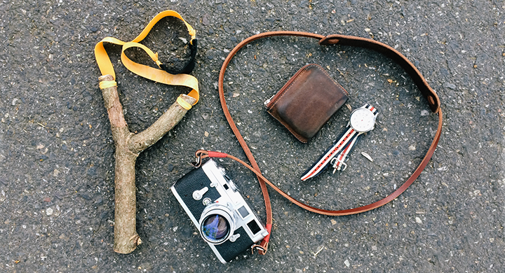  Camera, wallet, and slingshot sitting on pavement - Toggle Insurance 