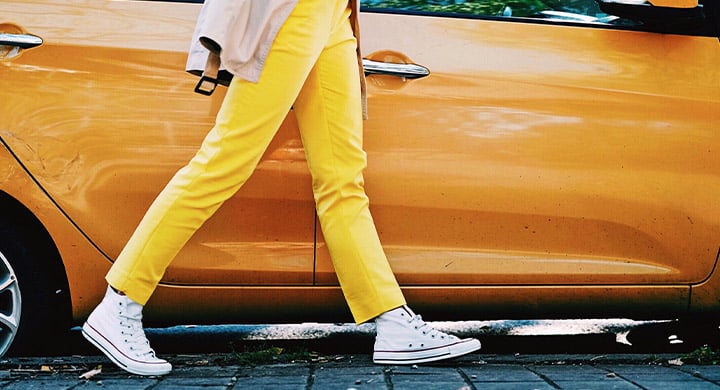 person in yellow pants walking by a yellow vehicle