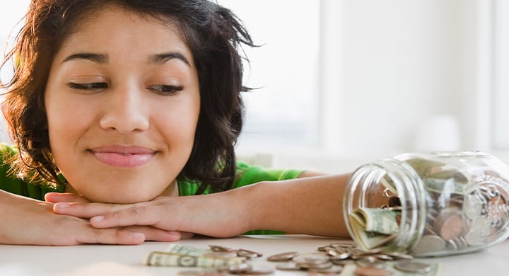 woman smiling and looking at spilled coins and cash on a table