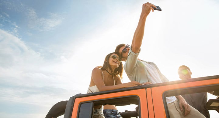 Happy young friends taking selfie during a road trip in a car