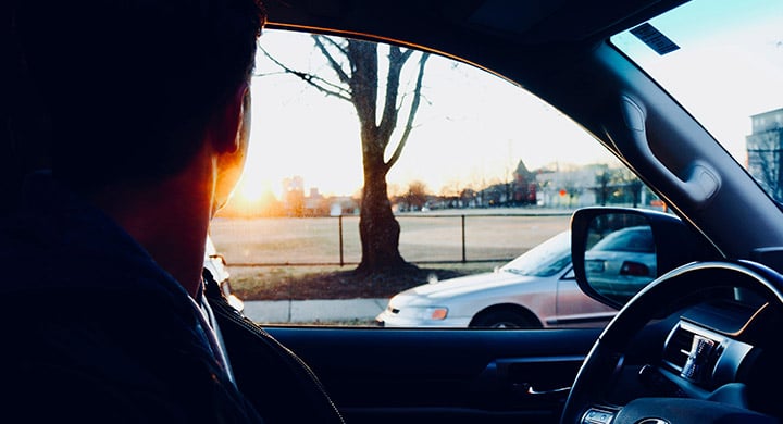 Man sitting inside car looking at sun