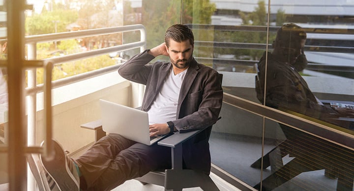 Man Working on His Computer on a Balcony